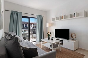 Un salon moderne avec un canapé, une table basse, un téléviseur et un balcon offrant une vue agréable.