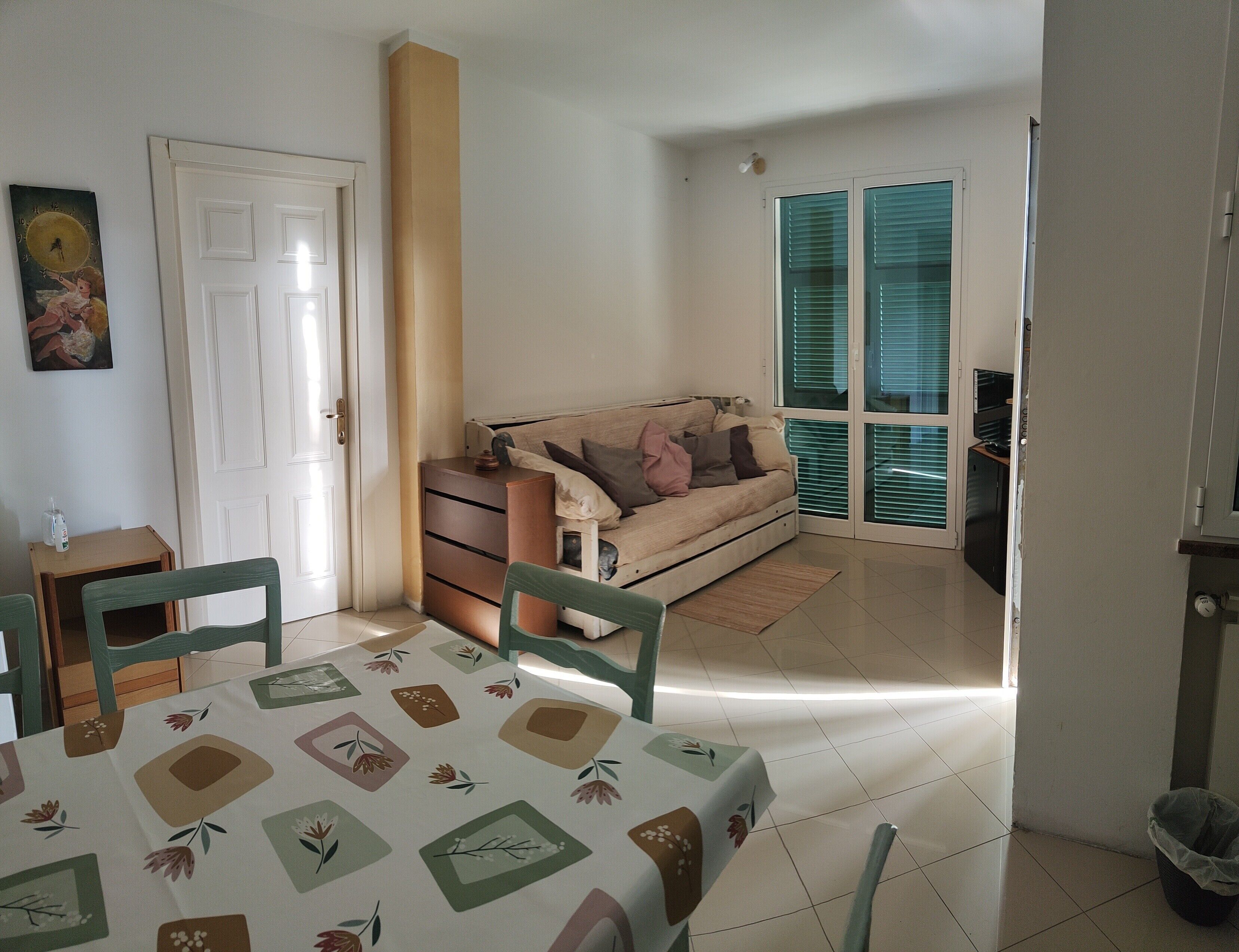 Habitació amb llit, taula, cadires, televisió i porta.
