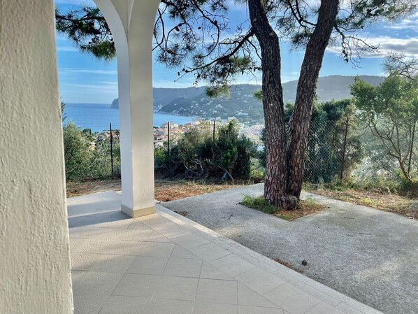 A covered outdoor area with a view of the sea and a town in the distance.