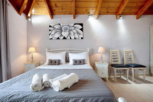 A bedroom with a bed, two bedside tables, a painting, and a chair.