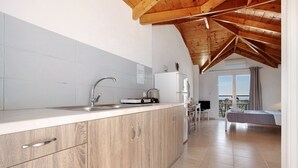Una cucina con mobili in legno, un lavello e un frigorifero. C'è un balcone con vista.