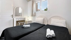 A hotel room with two beds, a desk, a chair, a mirror, and a window with curtains. - Holiday Apartment "Yiannis Superior Apartment" with Sea View, Wi-Fi & Garden (Zakynthos)