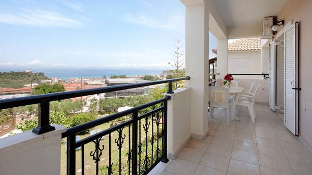 A balcony with a view of the sea, a table with chairs, and a potted plant. - Holiday Apartment "Yiannis Superior Apartment" with Sea View, Wi-Fi & Garden (Zakynthos)
