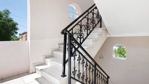 A staircase with a black wrought iron railing, white walls, and a small window. - Holiday Apartment "Yiannis Superior Apartment" with Sea View, Wi-Fi & Garden (Zakynthos)
