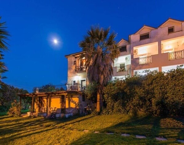 A two-story building with balconies, a covered outdoor seating area, and a well-maintained garden.