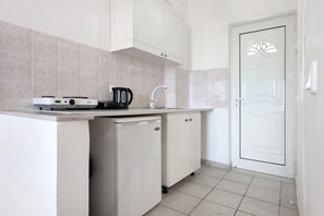 A kitchen with white cabinets, a countertop, a coffee maker, and a dishwasher.