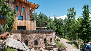 Un bâtiment en bois avec des murs en pierre, des places assises à l’extérieur et une vue sur les arbres.