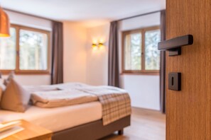 Ein Schlafzimmer mit einem Bett, Nachttischen, einer Wandleuchte und Fenstern.