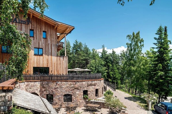 A wooden building with stone walls, outdoor seating, and a stone staircase.