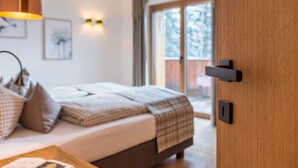 Ein Schlafzimmer mit Bett, Nachttisch, Lampe und Blick ins Freie.