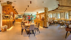 Un restaurante con interiores de madera, zona de bar y mesas de comedor con sillas.