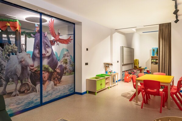 A children's room with a large wall mural, a play area, and a dining table with chairs.
