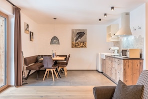 Une cuisine moderne avec un coin repas, des meubles en bois et un luminaire suspendu.