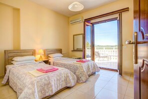 Una habitación de hotel con dos camas, un balcón y una puerta corrediza de vidrio.