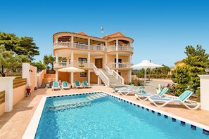 Un bâtiment à deux étages doté d’une piscine et de chaises longues.