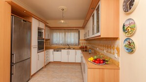 Une cuisine moderne équipée d’un réfrigérateur, d’un four à micro-ondes et d’un four en acier inoxydable, de meubles en bois, d’un pare-feu en carreaux et d’un plat de fruits posé sur le comptoir.