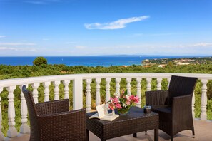 A balcony with wicker furniture, a table, and a vase of flowers.
