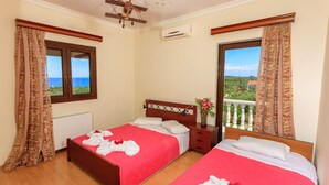 Une chambre d’hôtel avec deux lits, une tête de lit en bois, une fenêtre avec des rideaux, un radiateur et un balcon avec vue.