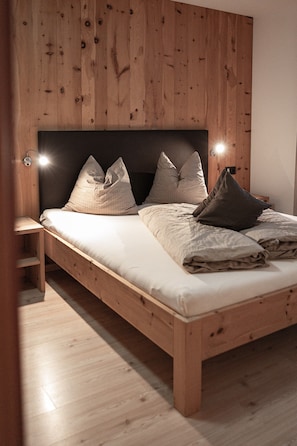 A wooden bed with a headboard, two bedside tables, and a nightstand.