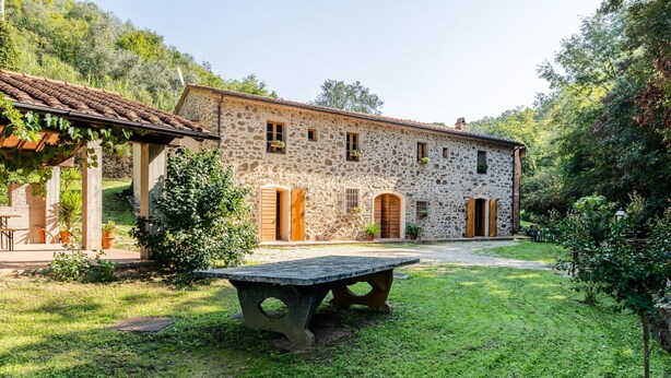 A stone building with a garden, a table, and a pergola. - Holiday Home "Mulino di Beboli" with Pool & Garden (Lamporecchio (PT))