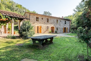 Un bâtiment en pierre doté d’un jardin, d’une table et d’une pergola.
