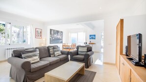Un salon moderne avec un ensemble de canapés, une table basse et un téléviseur posé sur un meuble en bois.