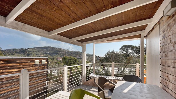 A covered outdoor area with a wooden ceiling, white railings, and a table with chairs. - "Mobile Home Next 229" with Pool, Garden & Wi-Fi (Pietra Ligure)