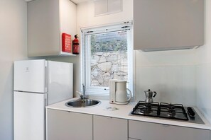 Une cuisine compacte équipée d’un réfrigérateur, d’un évier, d’une machine à café et d’une cuisinière à gaz.
