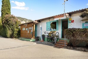 Un bâtiment d’accueil avec une enseigne, un vélo et une vue sur la montagne en arrière-plan.