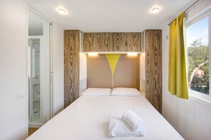A bedroom with a bed, a window with curtains, and a shower area. - 'Mobile Home Alloro 165' with Pool, Private Terrace & Wi-Fi (Pietra Ligure)
