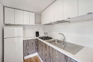 A modern kitchen with white cabinets, a stainless steel sink, a gas stove, and a coffee maker. - 'Mobile Home Alloro 165' with Pool, Private Terrace & Wi-Fi (Pietra Ligure)