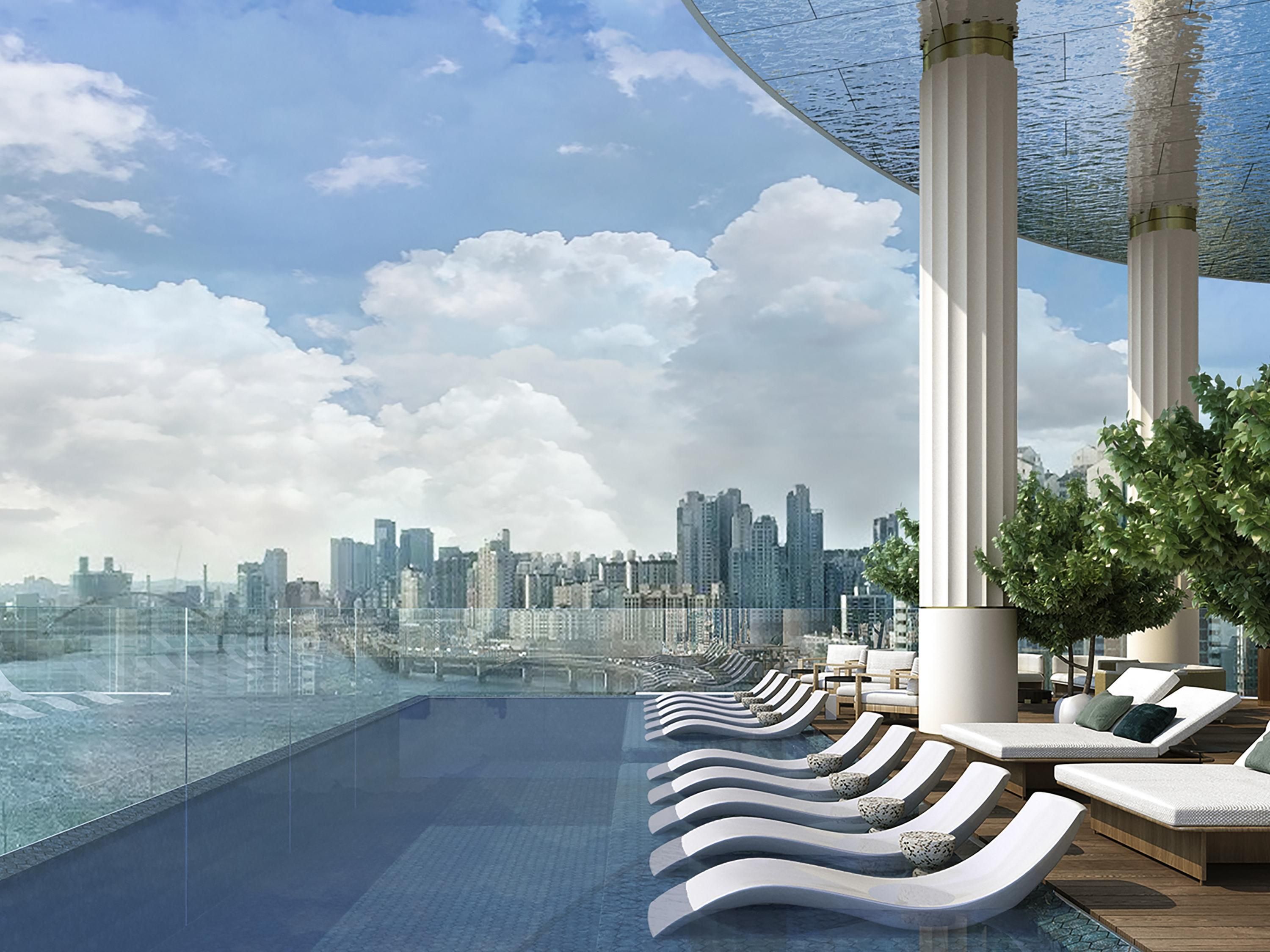 A rooftop infinity pool with lounge chairs and a city skyline view.