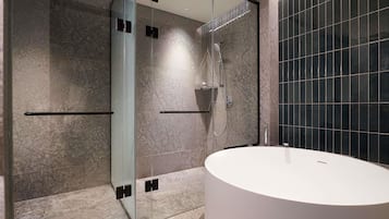 A modern bathroom with a glass shower enclosure, a white sink, and tiled walls.