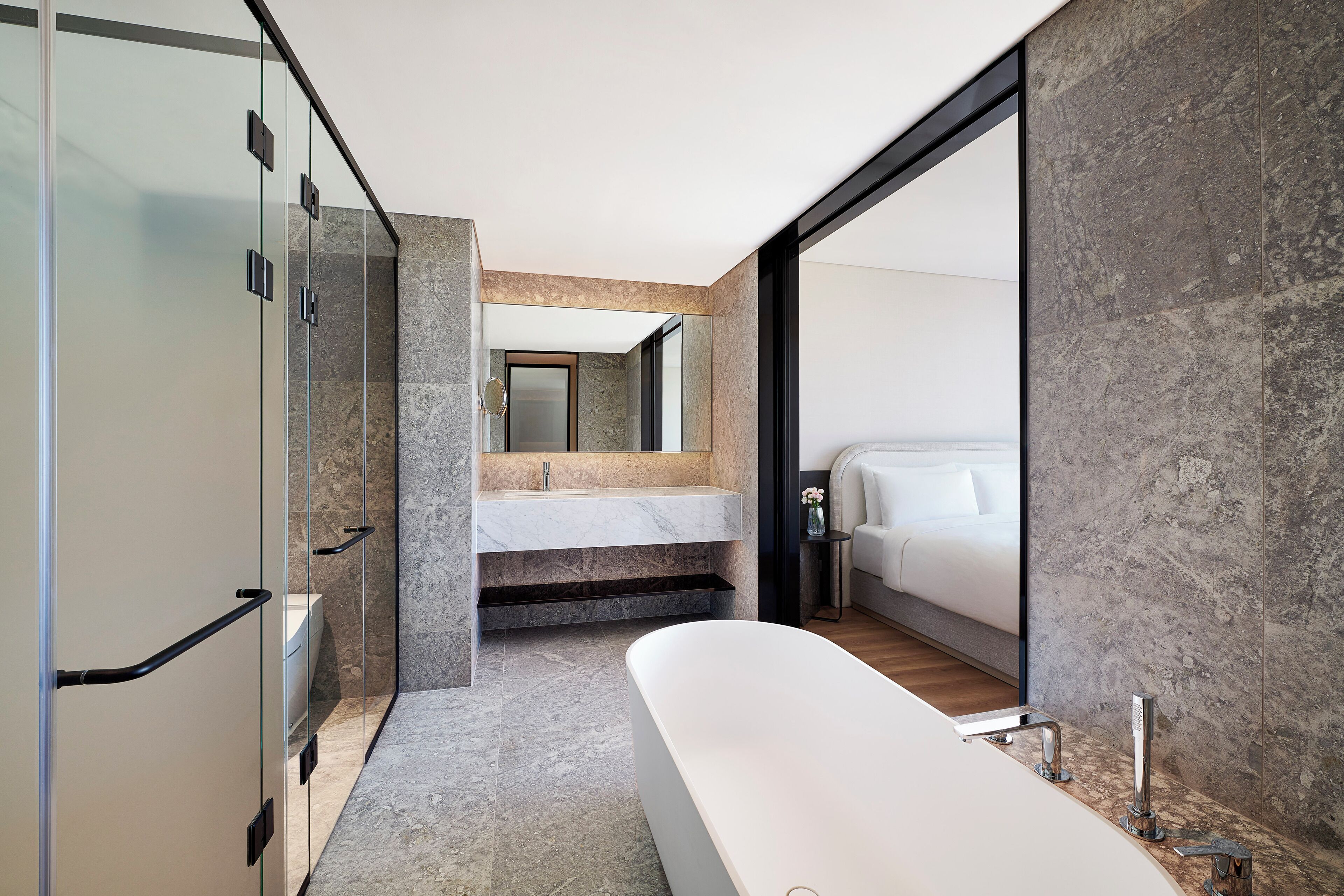 Un baño moderno con cabina de ducha de vidrio, una bañera independiente y un tocador de mármol.