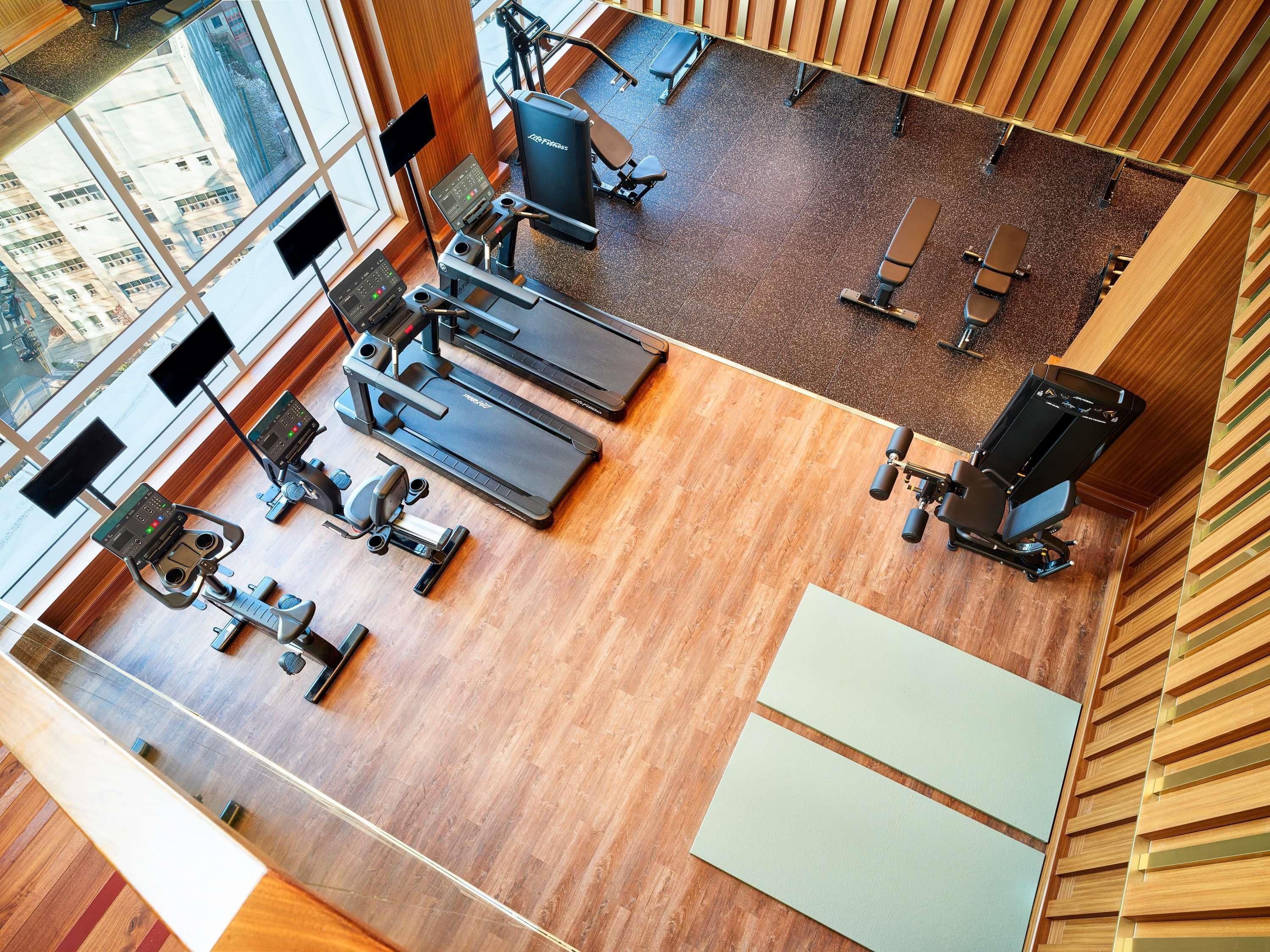 Un gimnasio con cintas de correr, bicicletas estáticas y máquinas de pesas.
