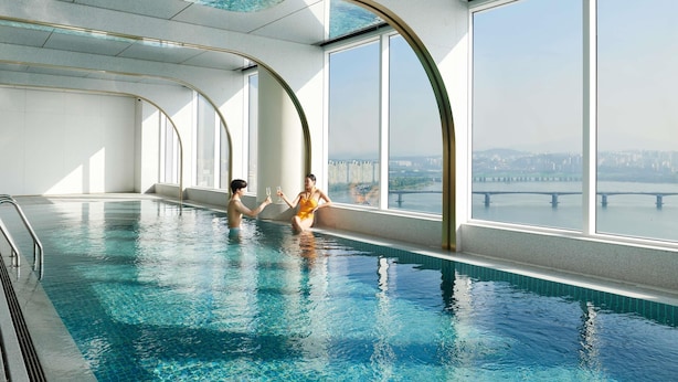 Piscina interior con vistas despejadas a un paisaje urbano a través de amplias ventanas.