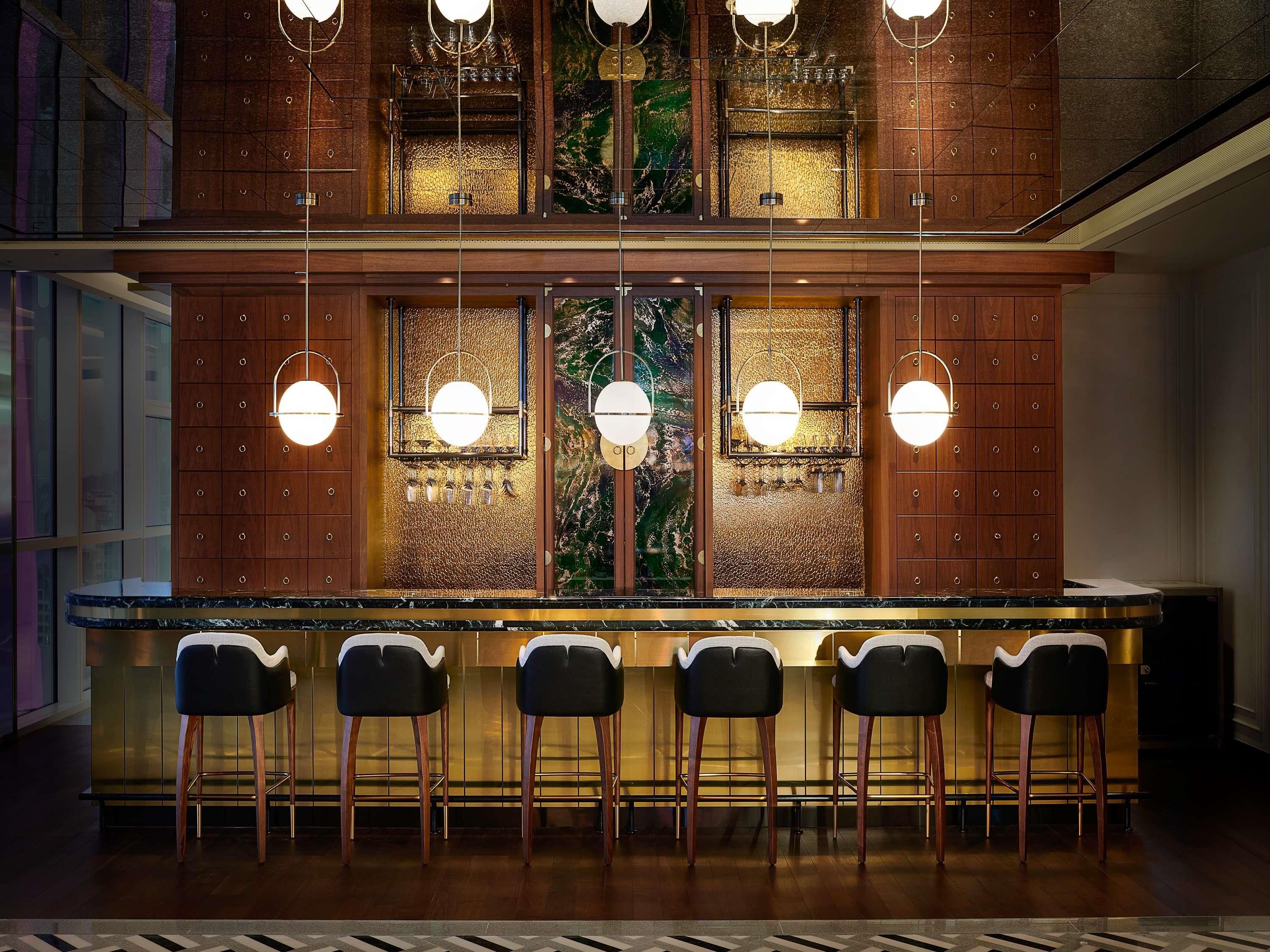 A bar area with a wooden counter and six bar stools.