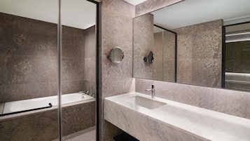 Une salle de bain moderne avec une douche à l’italienne en verre, un lavabo en marbre et un grand miroir.