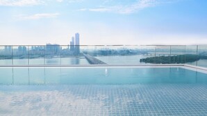 A rooftop infinity pool with a city skyline view, a glass railing, and a tiled floor. - Hotel Naru Seoul - MGallery Collection (Seoul)