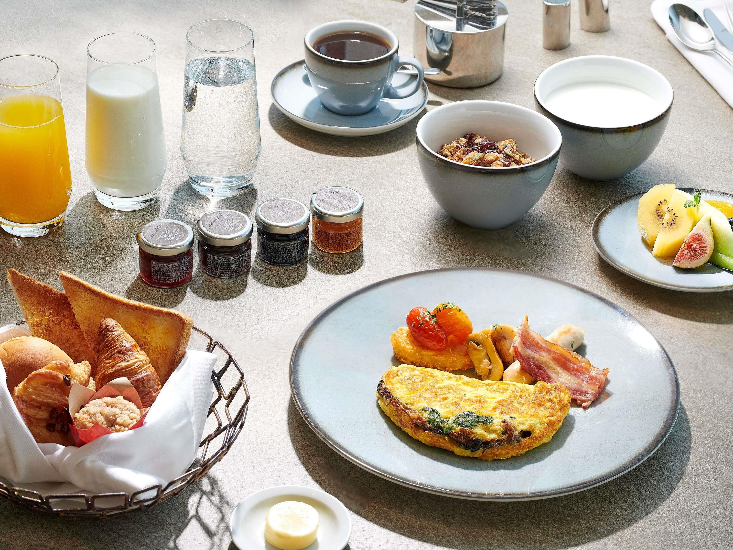 A breakfast table with various food items, beverages, and condiments.