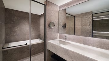 A modern bathroom with a glass shower enclosure, a large mirror, and a marble countertop.