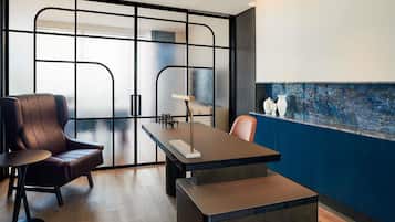 Quarto moderno com piso de madeira, uma poltrona de couro marrom, uma mesa de madeira e uma parede azul decorativa.