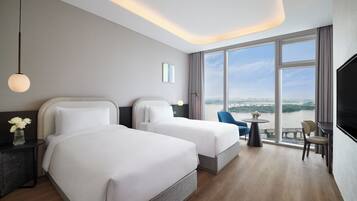 Une chambre d’hôtel avec deux lits, une télévision, un bureau et une vue sur une rivière et le paysage urbain.