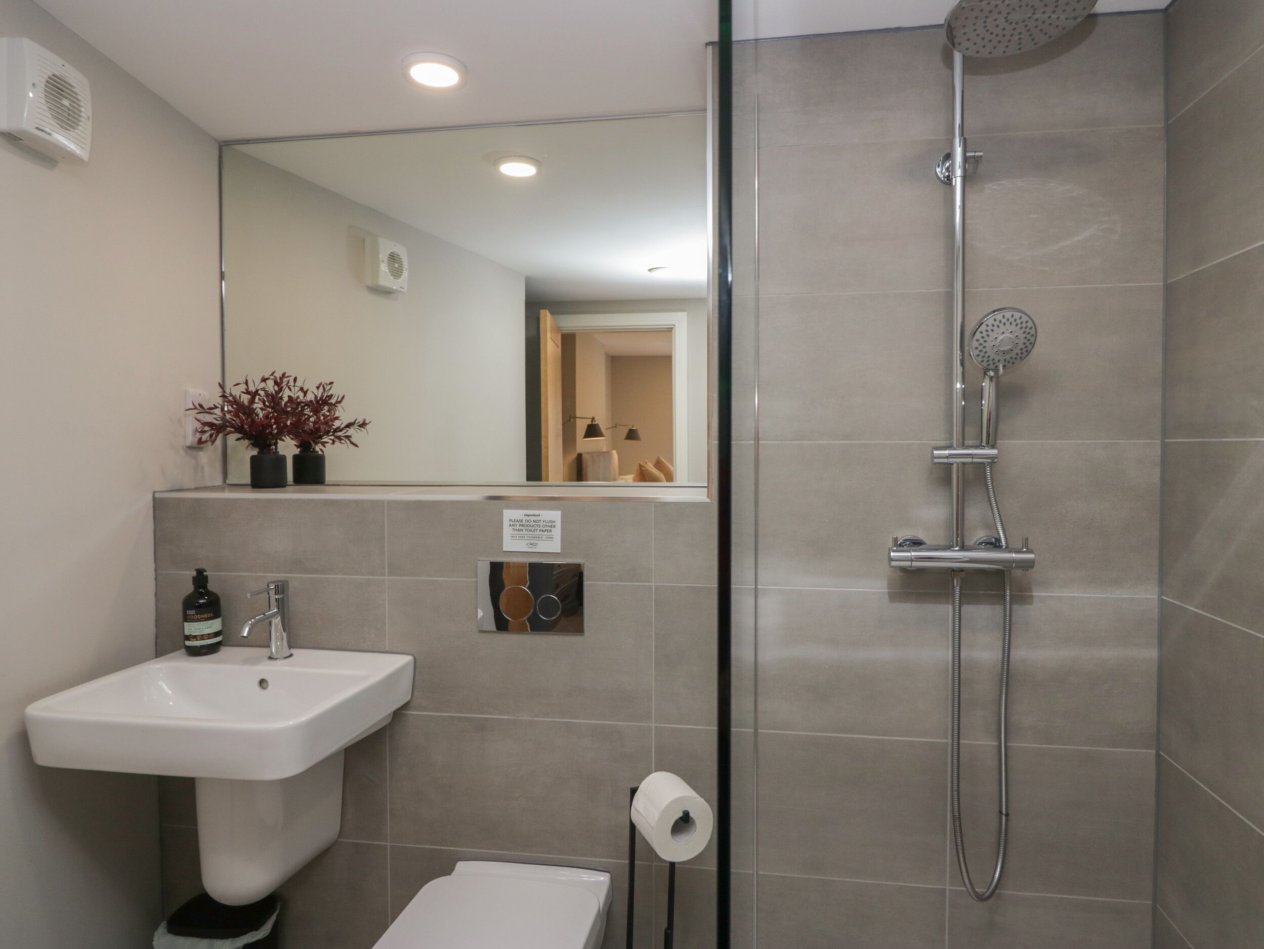 Une salle de bain moderne équipée d’un lavabo, de toilettes et d’une douche.
