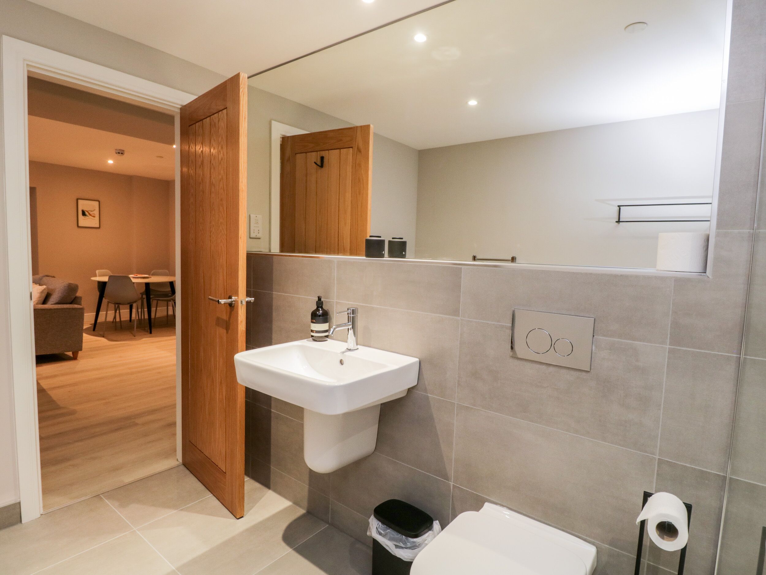 A modern bathroom with a white sink, a toilet, and a mirror.