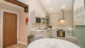 Une cuisine moderne avec des meubles blancs, un four encastré et une table ronde en marbre.