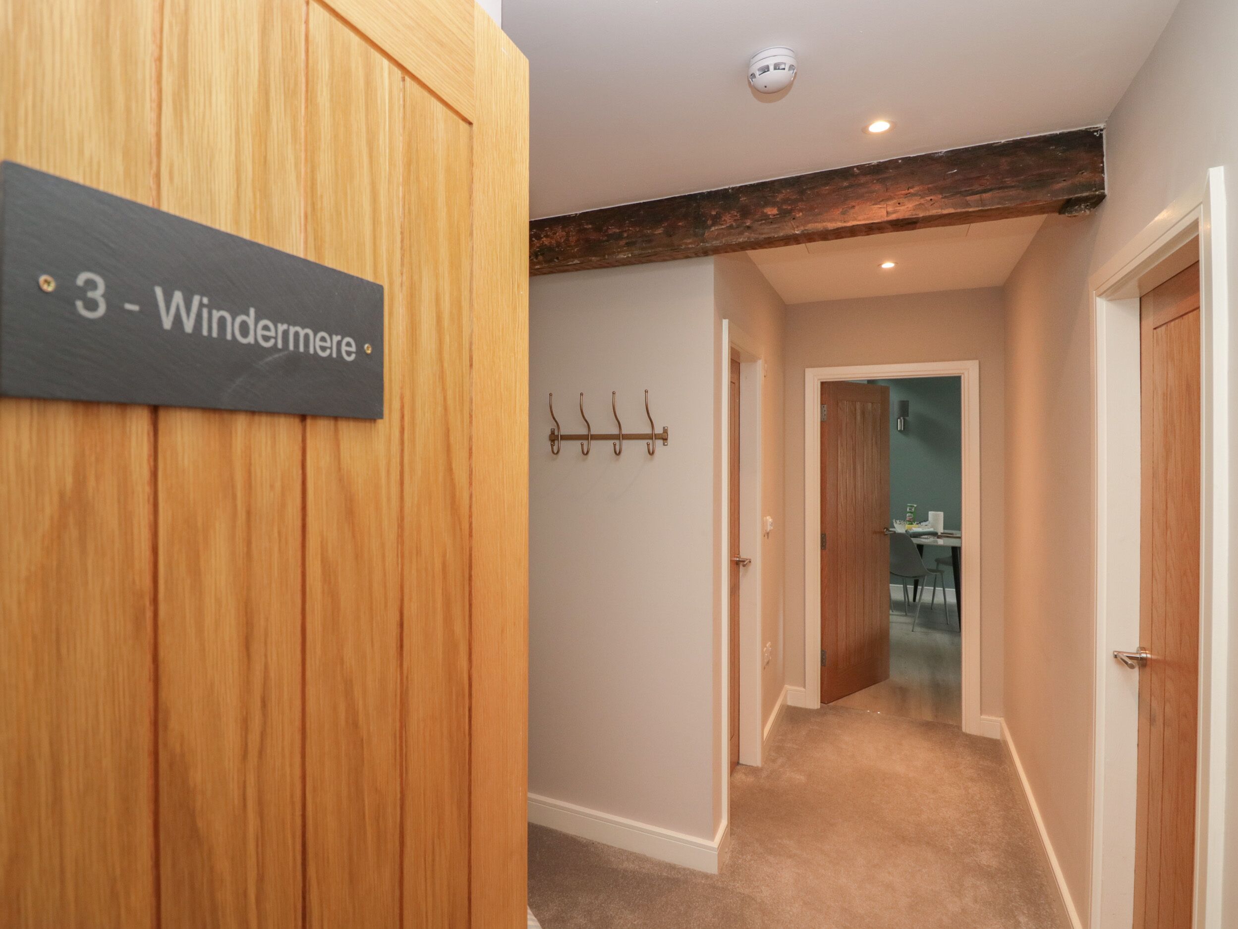 A hallway with a wooden door labeled "3 - Windermere" and a coat rack.