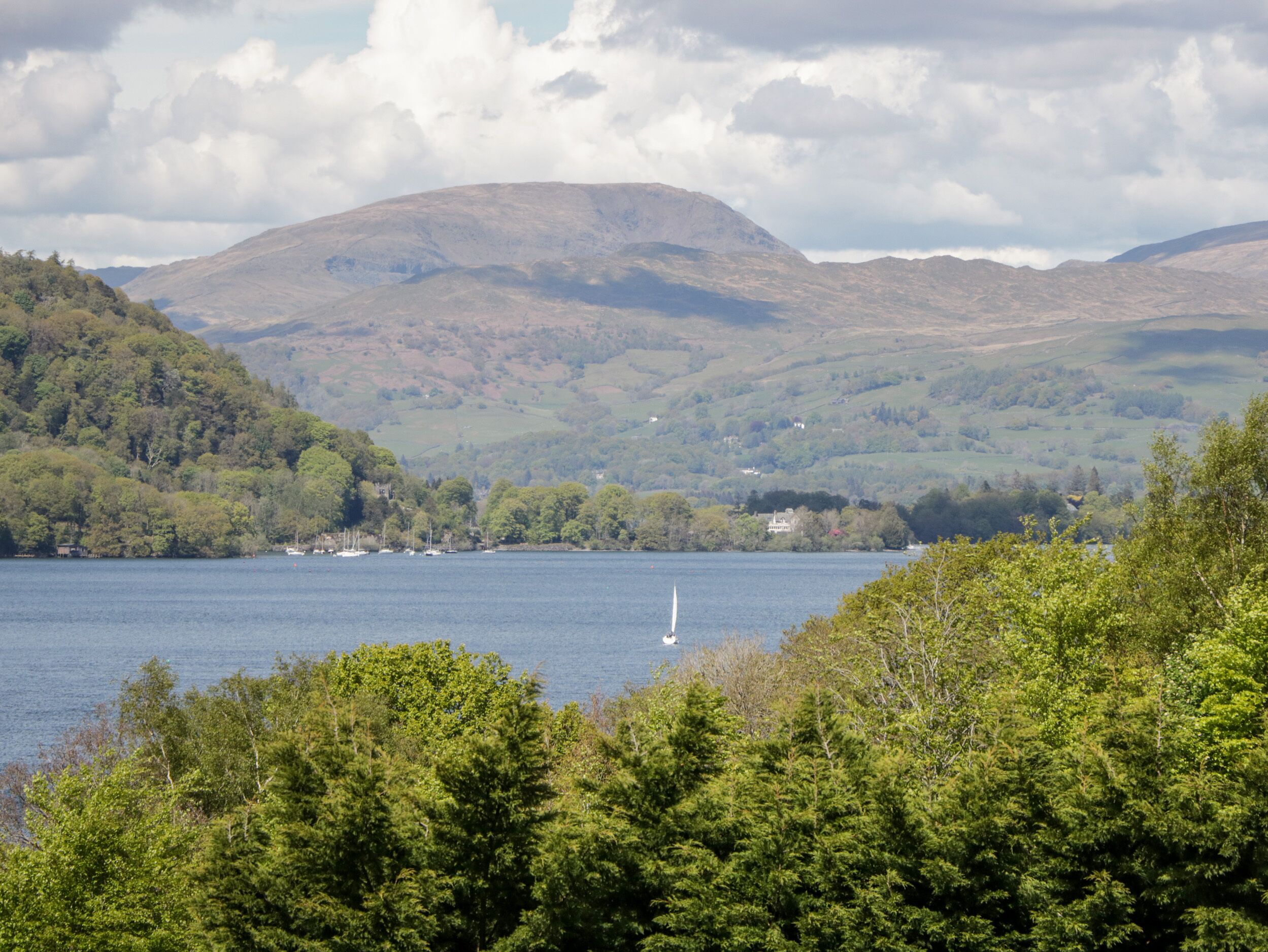 A lake surrounded by hills with a sailboat in the water.