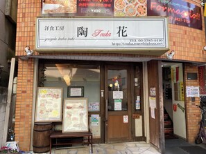 Ein Schaufenster mit einem Schild, das den Namen 'Yoshikou Toukou Touka' und Kontaktinformationen zeigt.
