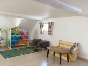 Ein Kinderzimmer mit einer hölzernen Bank, einer Spielmatte und einem farbenfrohen Stauraum.
